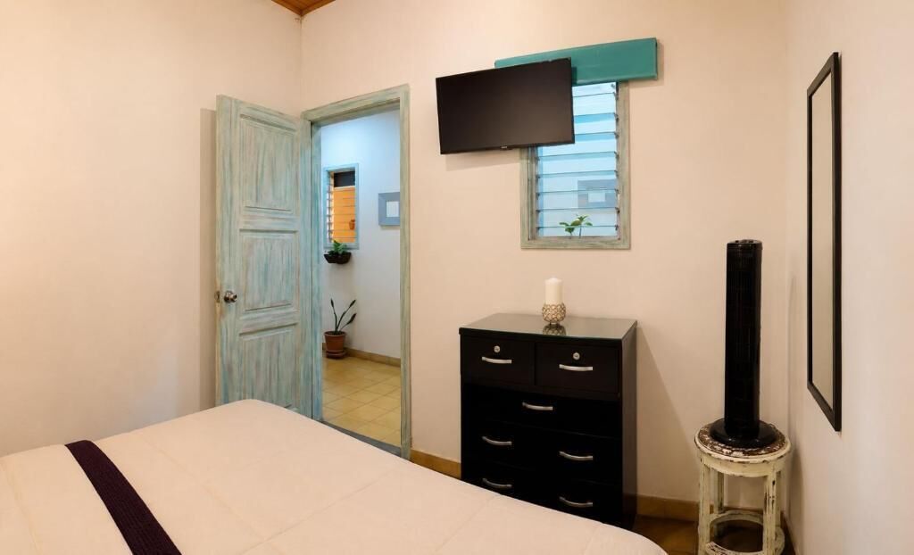 A bedroom with a bed, a dresser, a television, and a window.