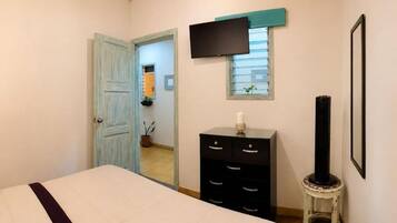 A bedroom with a bed, a dresser, a television, and a window.