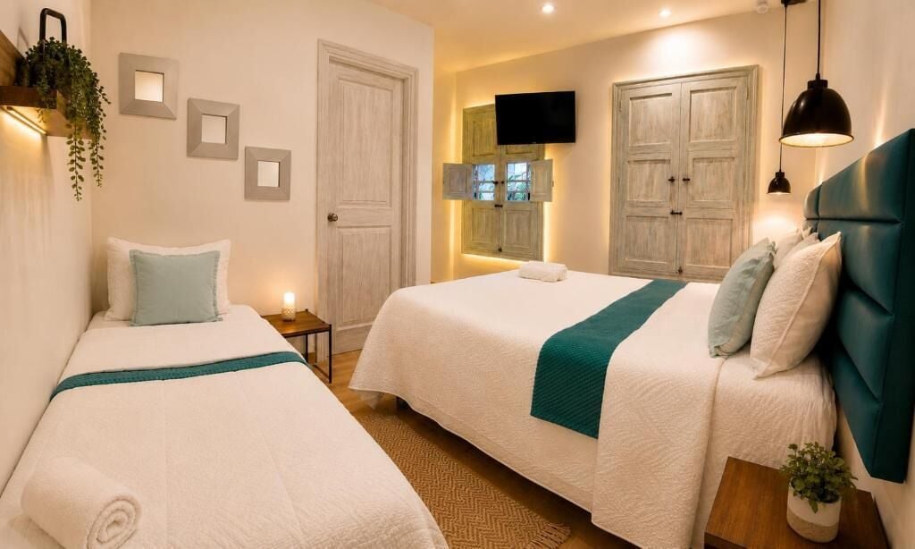 A hotel room with two beds, a television, and a wall-mounted TV.