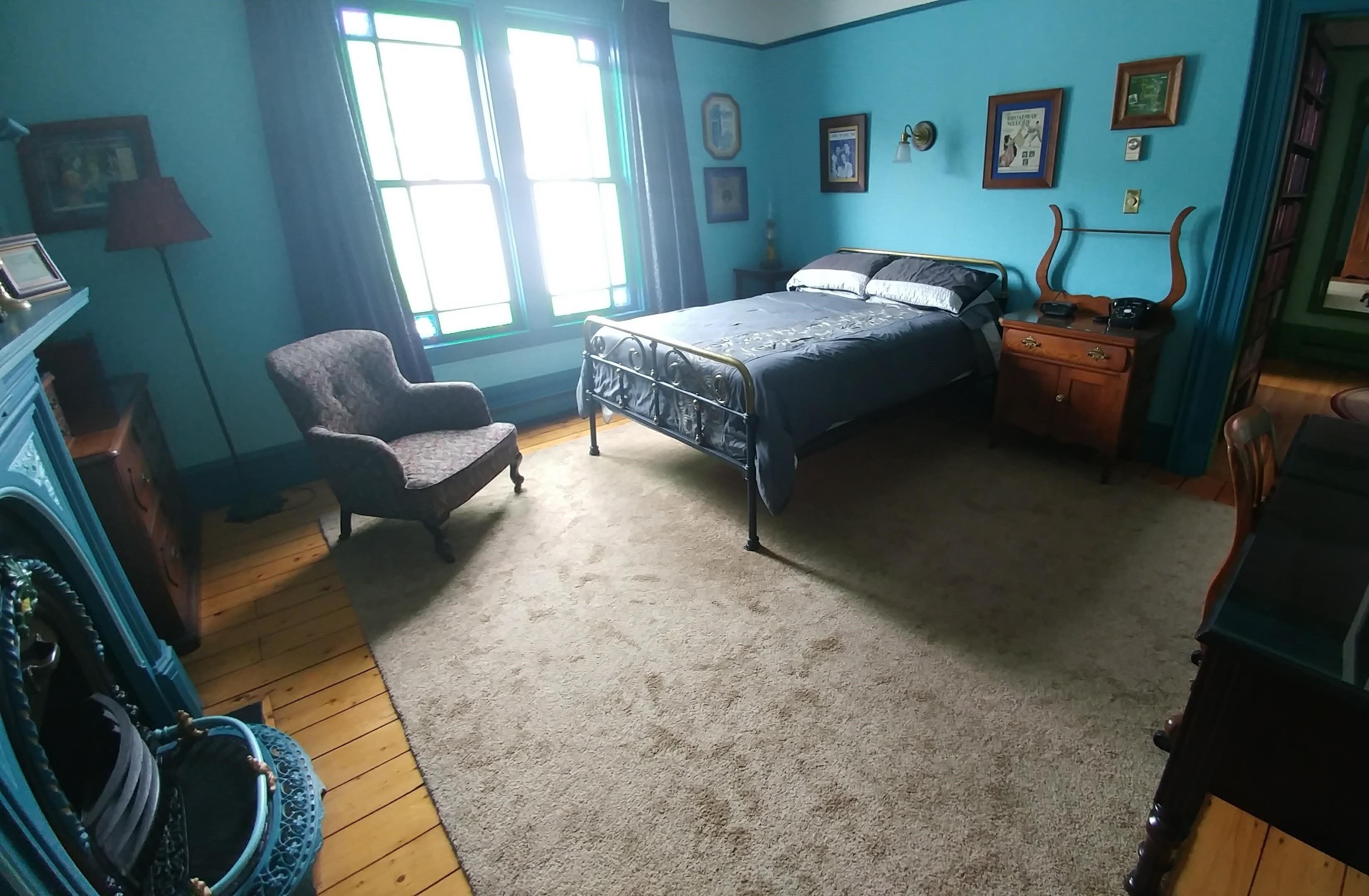 Ein Schlafzimmer mit Bett, Stuhl, Schminktisch und Fenster.