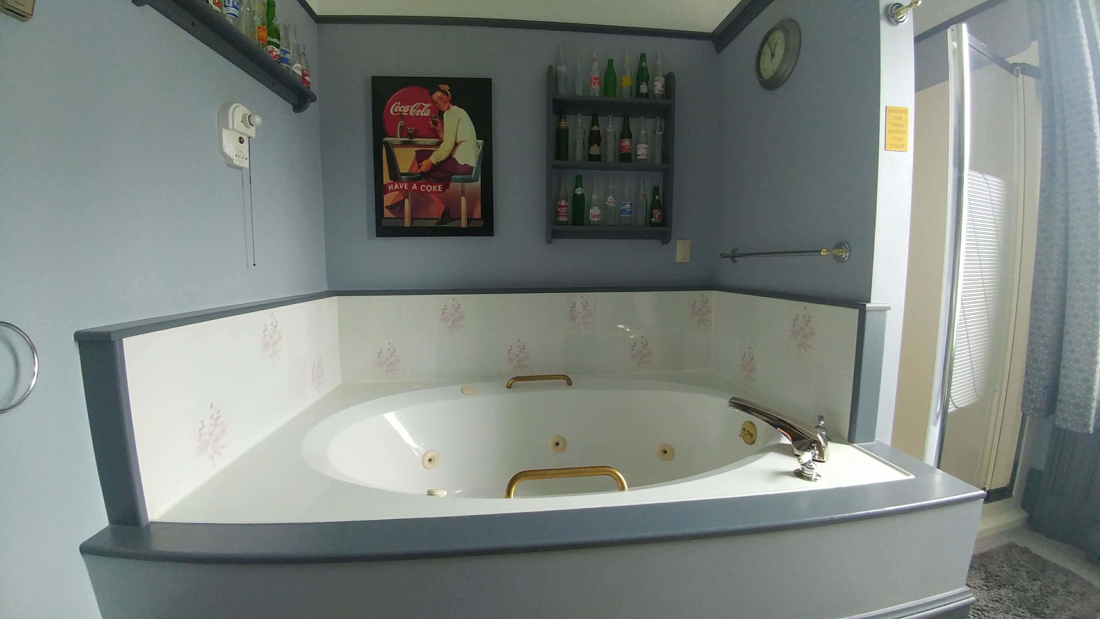 A bathroom with a large bathtub, a wall-mounted clock, and shelves with toiletries.