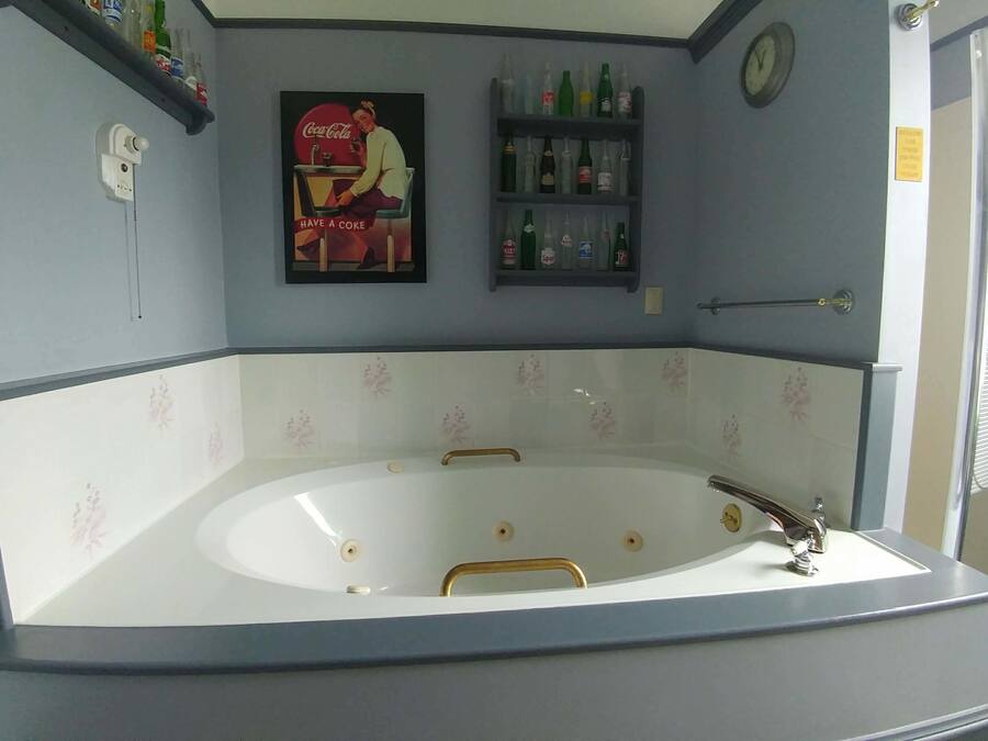 A bathroom with a large bathtub, a wall-mounted clock, and shelves with toiletries.