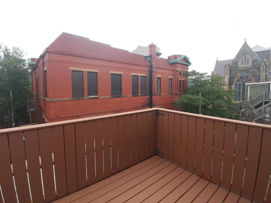 Un balcone in legno con vista su un edificio in mattoni rossi e una chiesa con tetto a punta.