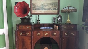 A vintage wooden desk with multiple drawers, a phonograph, a framed historical map, and a lamp. - Gower Manor Historical Bed & Breakfast (St. John's)
