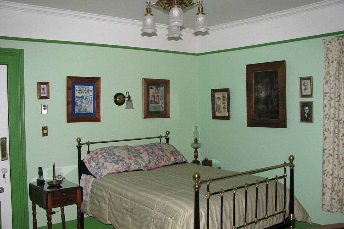 A bedroom with a bed, bedside table, lamp, and wall-mounted light fixture.