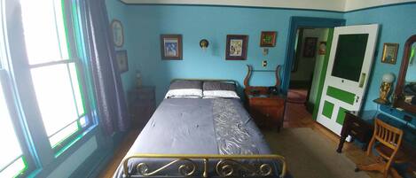 A room with a bed, a desk, and a chair. There are pictures on the wall and a door with a green and white design.