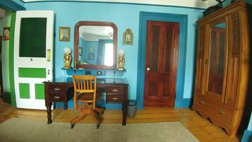 A room with a desk, chair, wardrobe, and a door with a green panel.