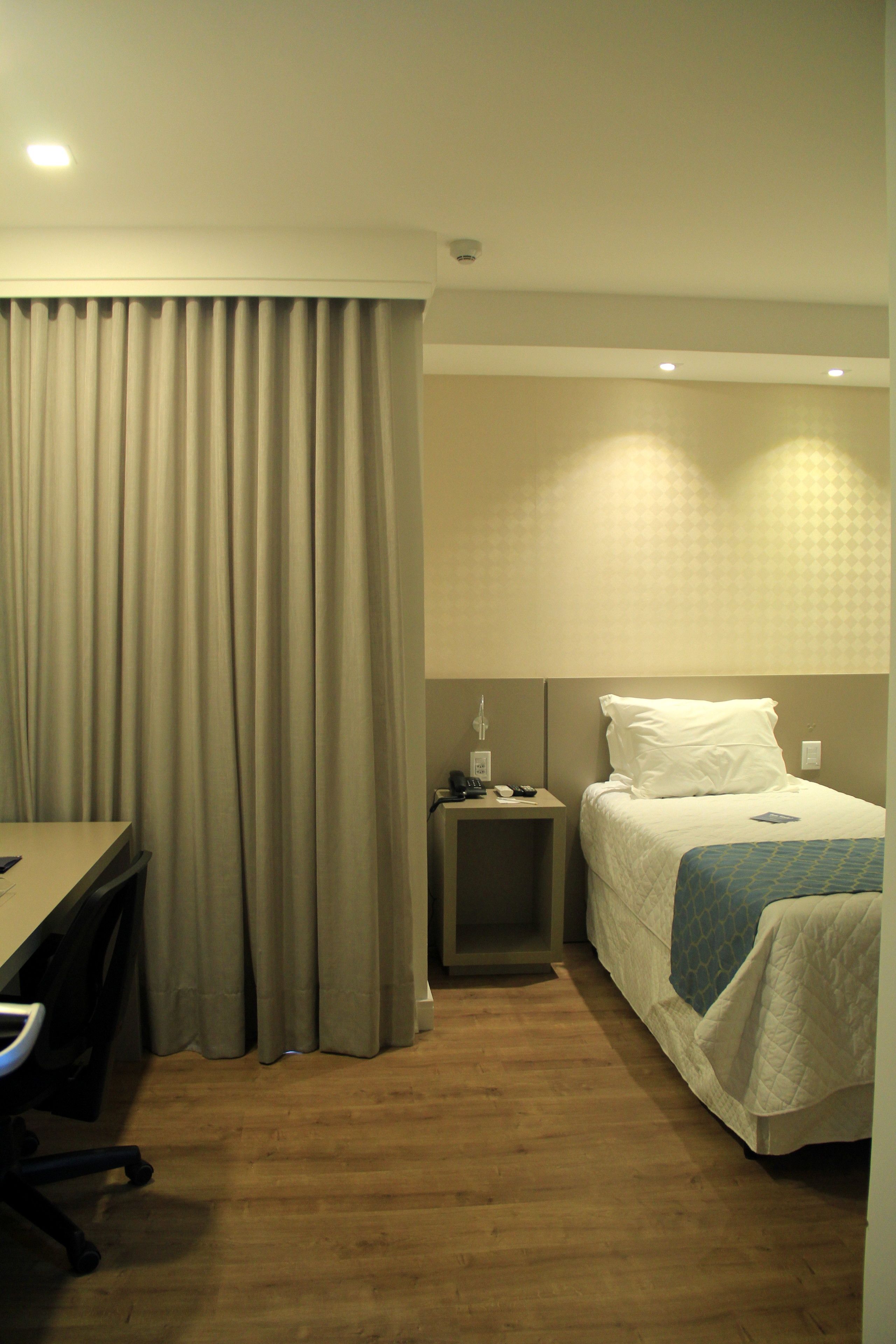 Una habitación de hotel con cama, escritorio y mesita de noche.