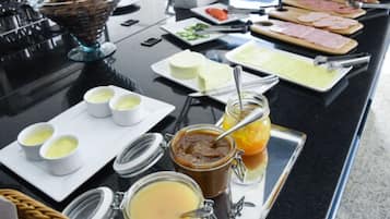 Un bufé con una variedad de alimentos, incluyendo carnes, quesos y salsas.