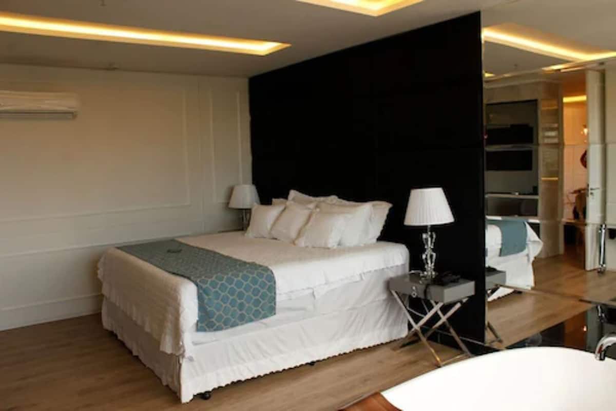 A modern hotel room with a large bed, bedside tables, a desk, and a bathroom.