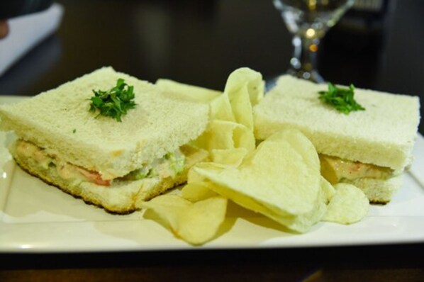 Un sándwich de lechuga y tomate, acompañado de papas fritas en un plato blanco.
