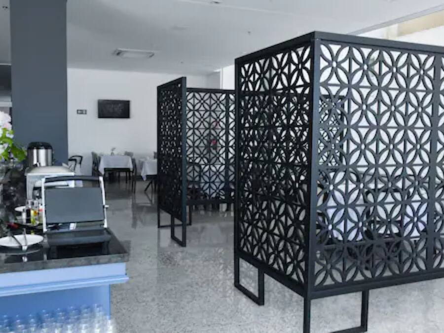 Un moderno vestíbulo de hotel con mostrador de recepción, zona de estar y separadores decorativos de metal negro.