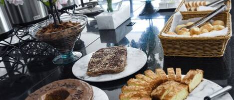A buffet table with various pastries and desserts, including a chocolate cake and a fruit tart.