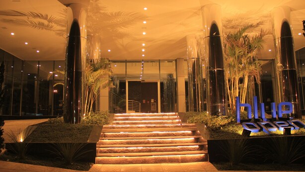 A hotel entrance with a well-lit staircase, palm trees, and a sign that reads "Hotel Open". - Blue Open Hotel (Erechim)
