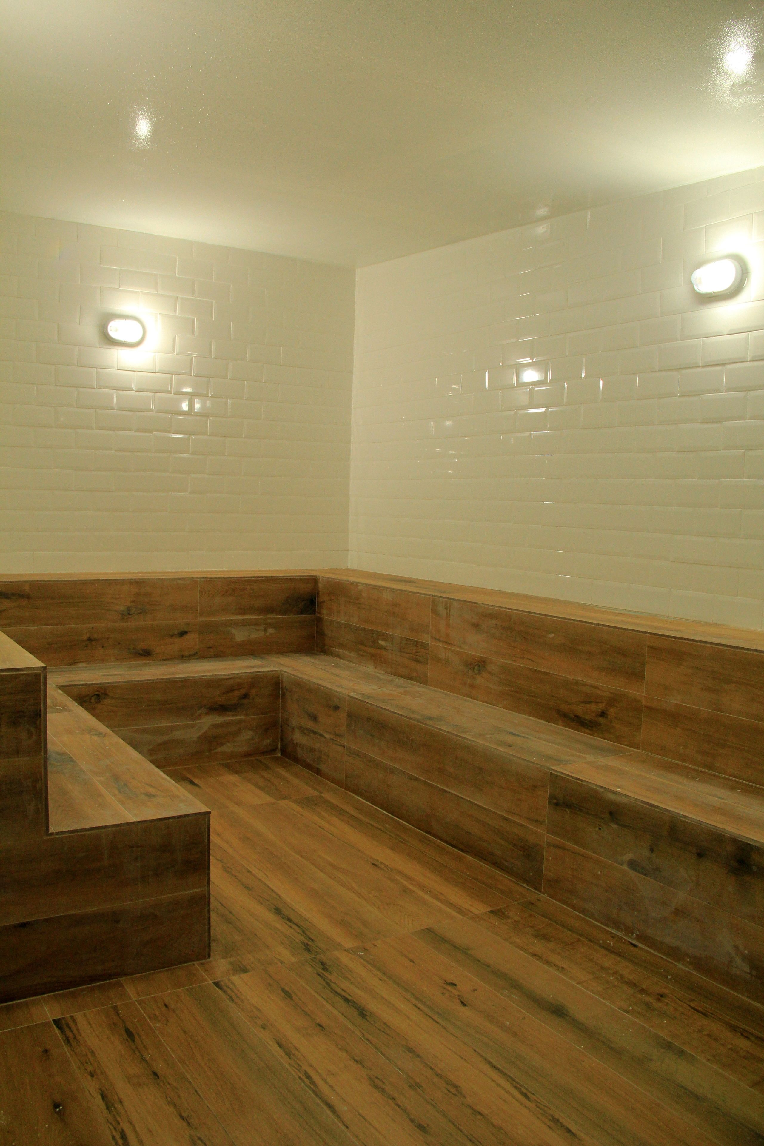 A room with wooden benches and white tiled walls.