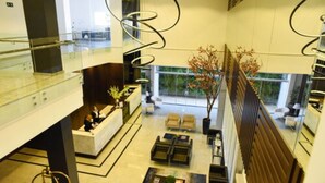 A modern lobby with a reception desk, seating area, and a large window offering a view of the outdoors. - Blue Open Hotel (Erechim)