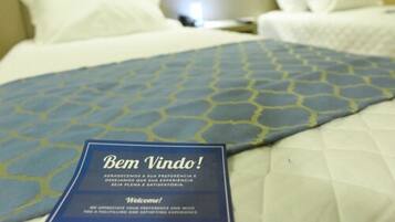Una habitación de hotel con cama, almohadas y un cartel de bienvenida.