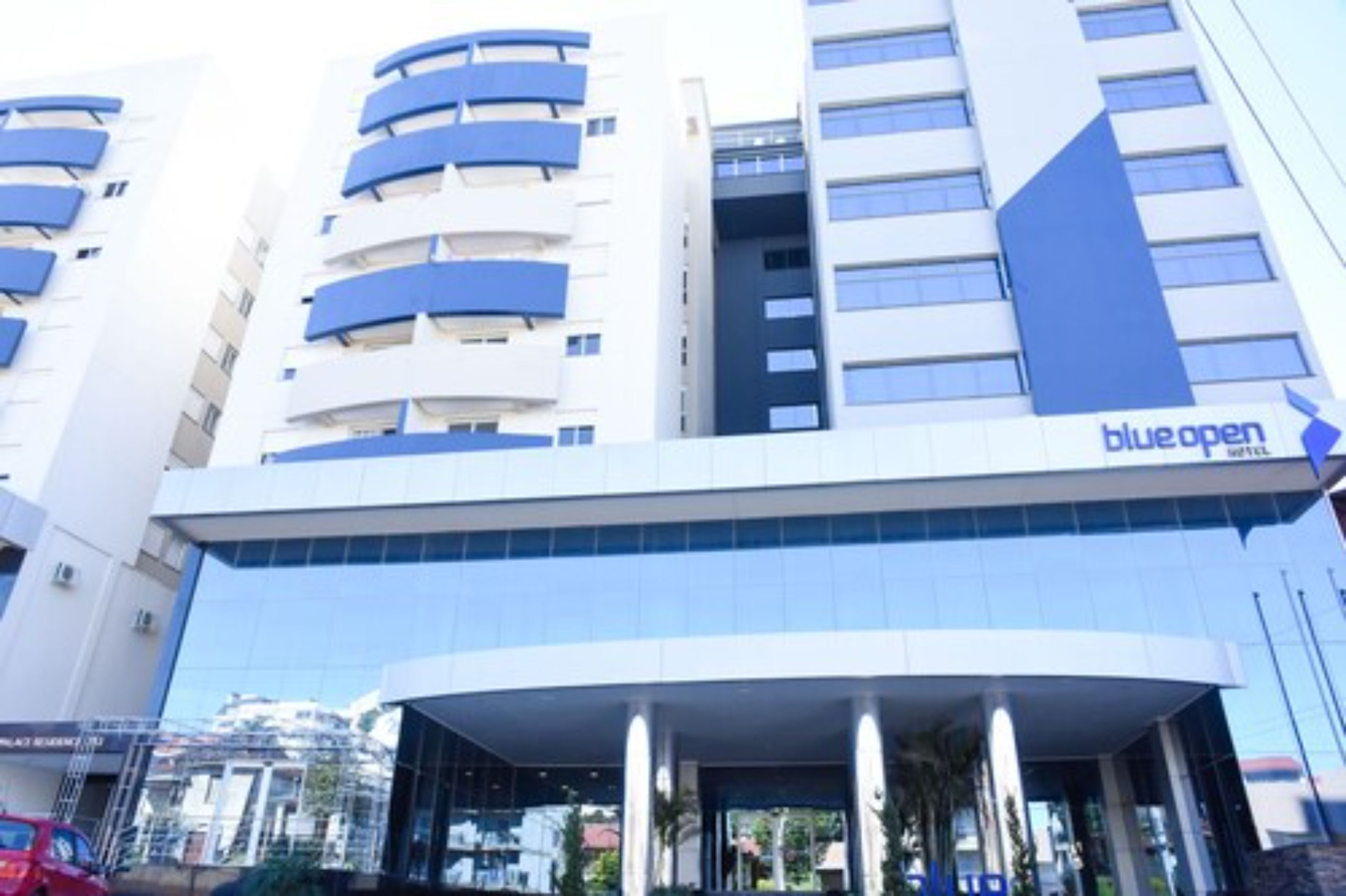 Un moderno edificio hotelero con llamativos colores azul y blanco, que presenta una entrada curva y varios balcones.