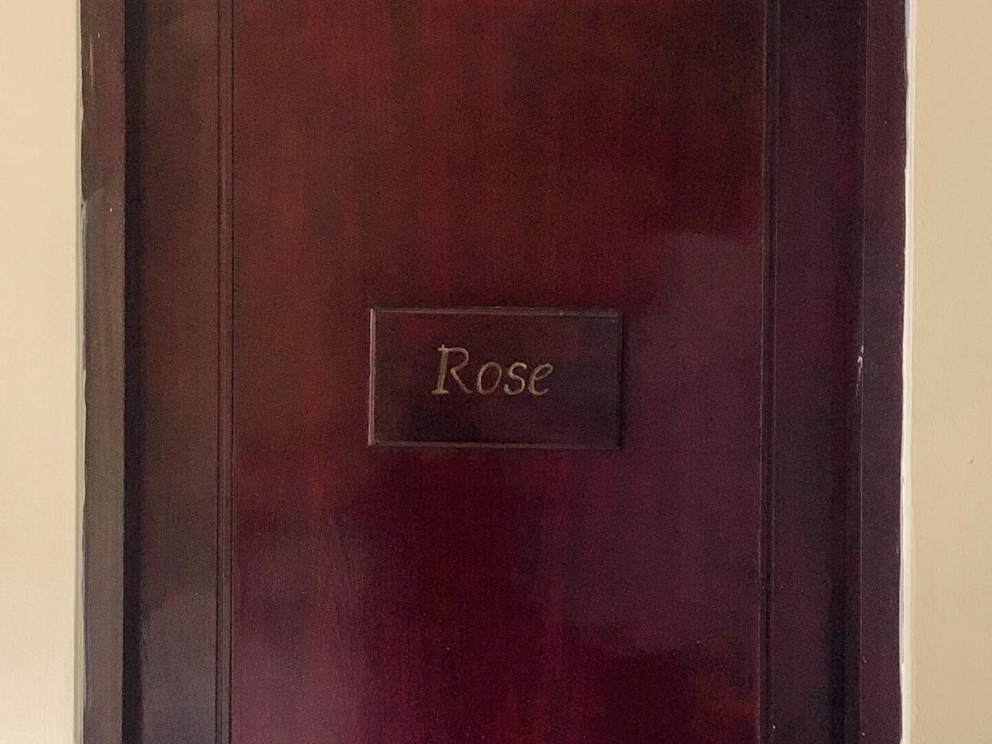 A dark red door with a nameplate that reads "Rose".