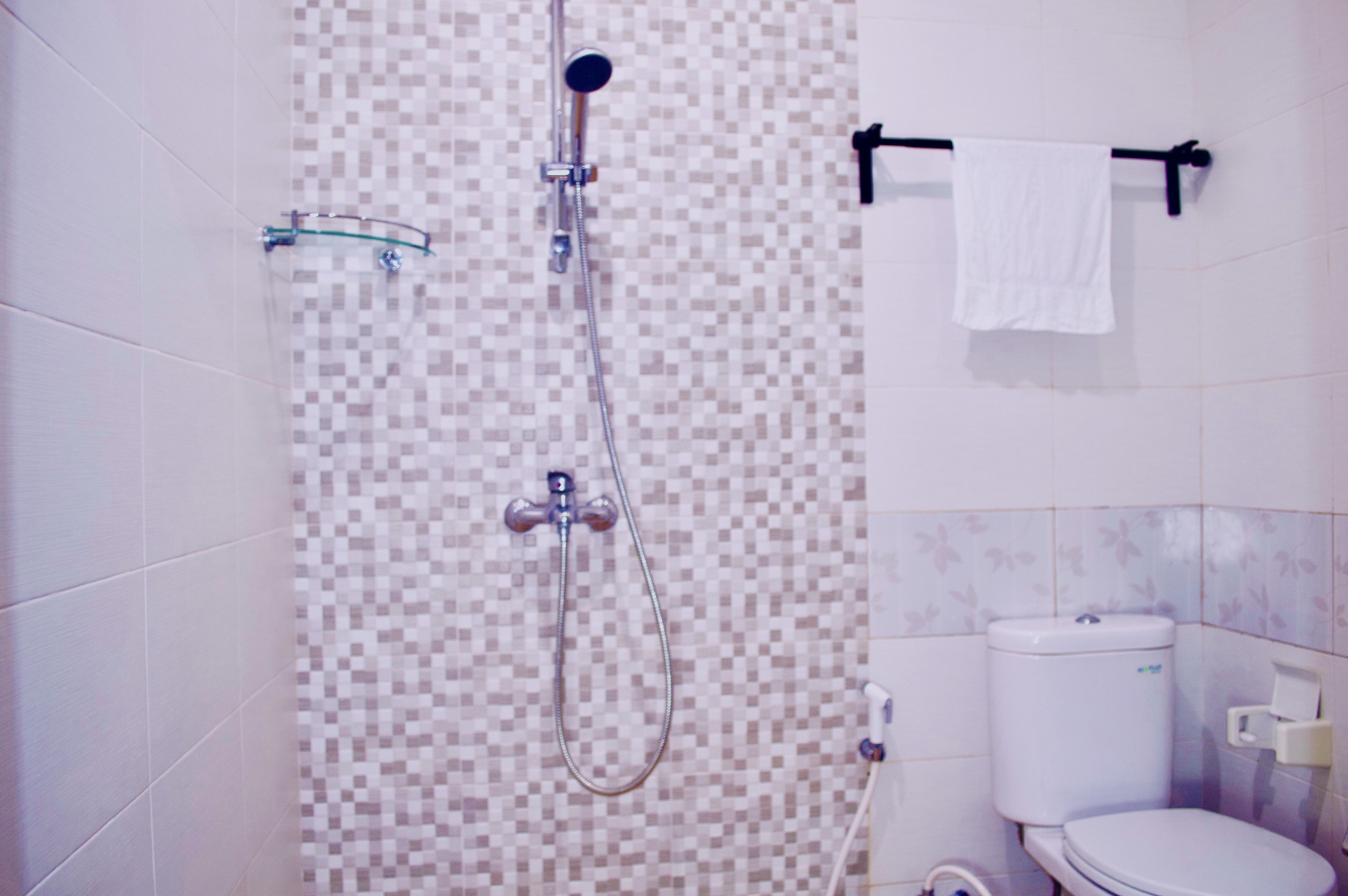 Un baño con ducha, inodoro y toallero.