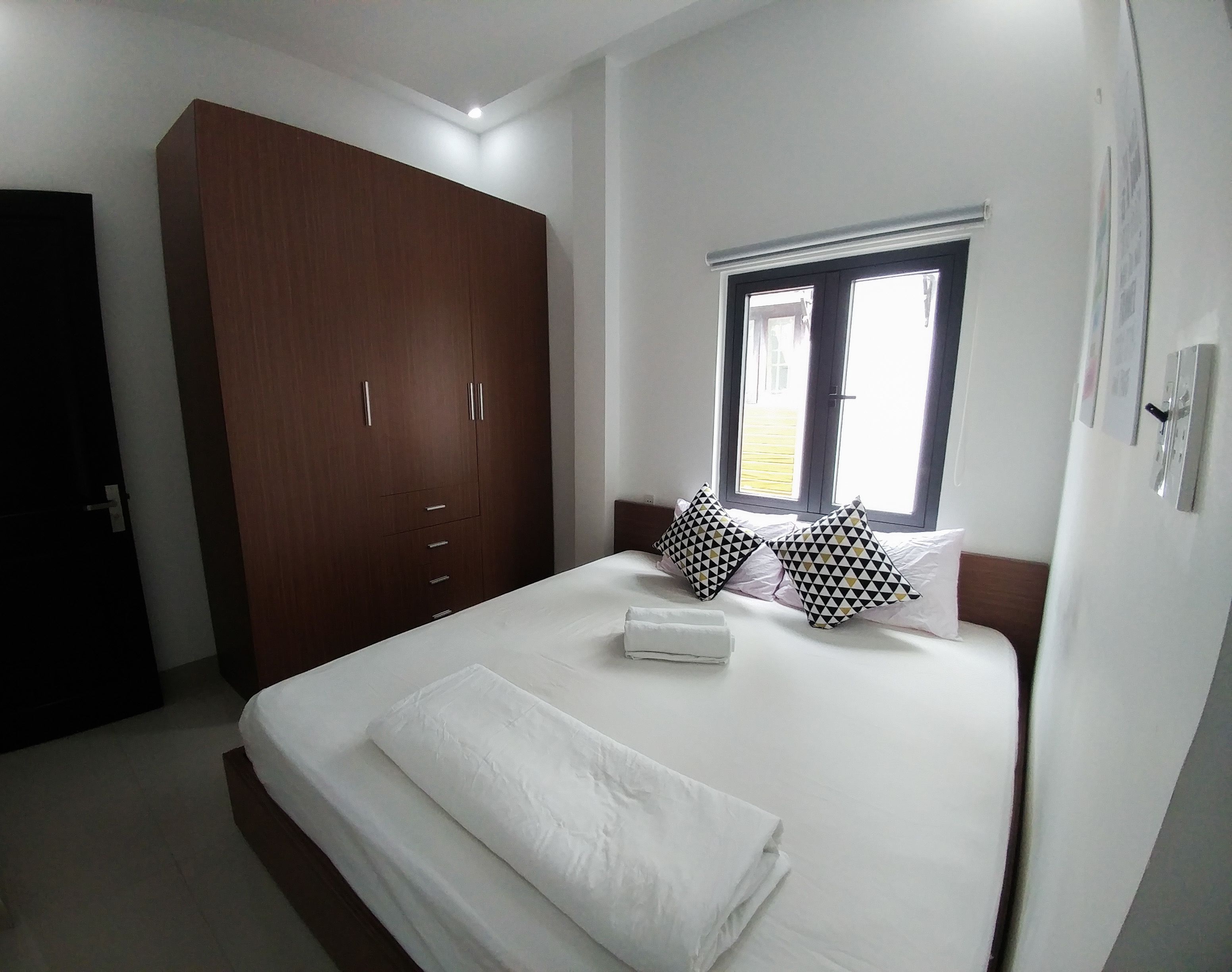 A bedroom with a large bed, a wardrobe, and a window.
