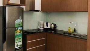 A modern kitchen with a refrigerator, a coffee maker, a kettle, and a sink. - Cukoo House (Hanoi)