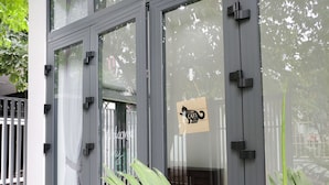 A modern building with large glass windows and a wooden door. - Cukoo House (Hanoi)