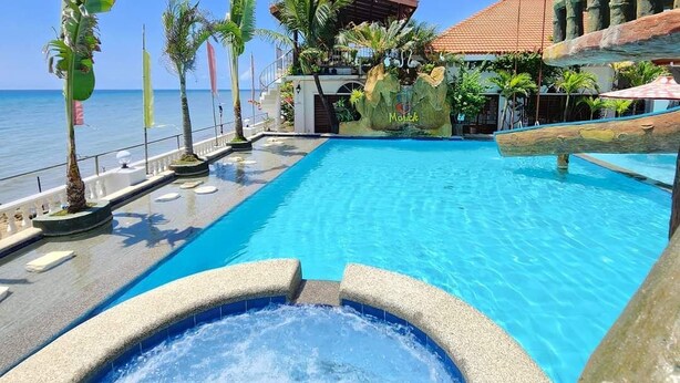 A swimming pool with a hot tub, palm trees, and a building with a red roof. - Marick Beach Resort (Carmen)
