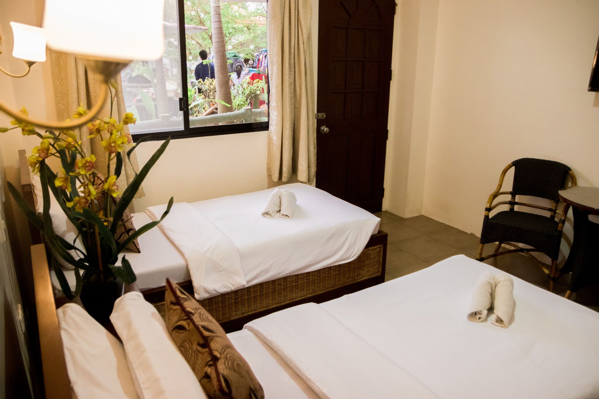 Une chambre d’hôtel avec deux lits, une fenêtre donnant sur l’extérieur, une chaise et une table.
