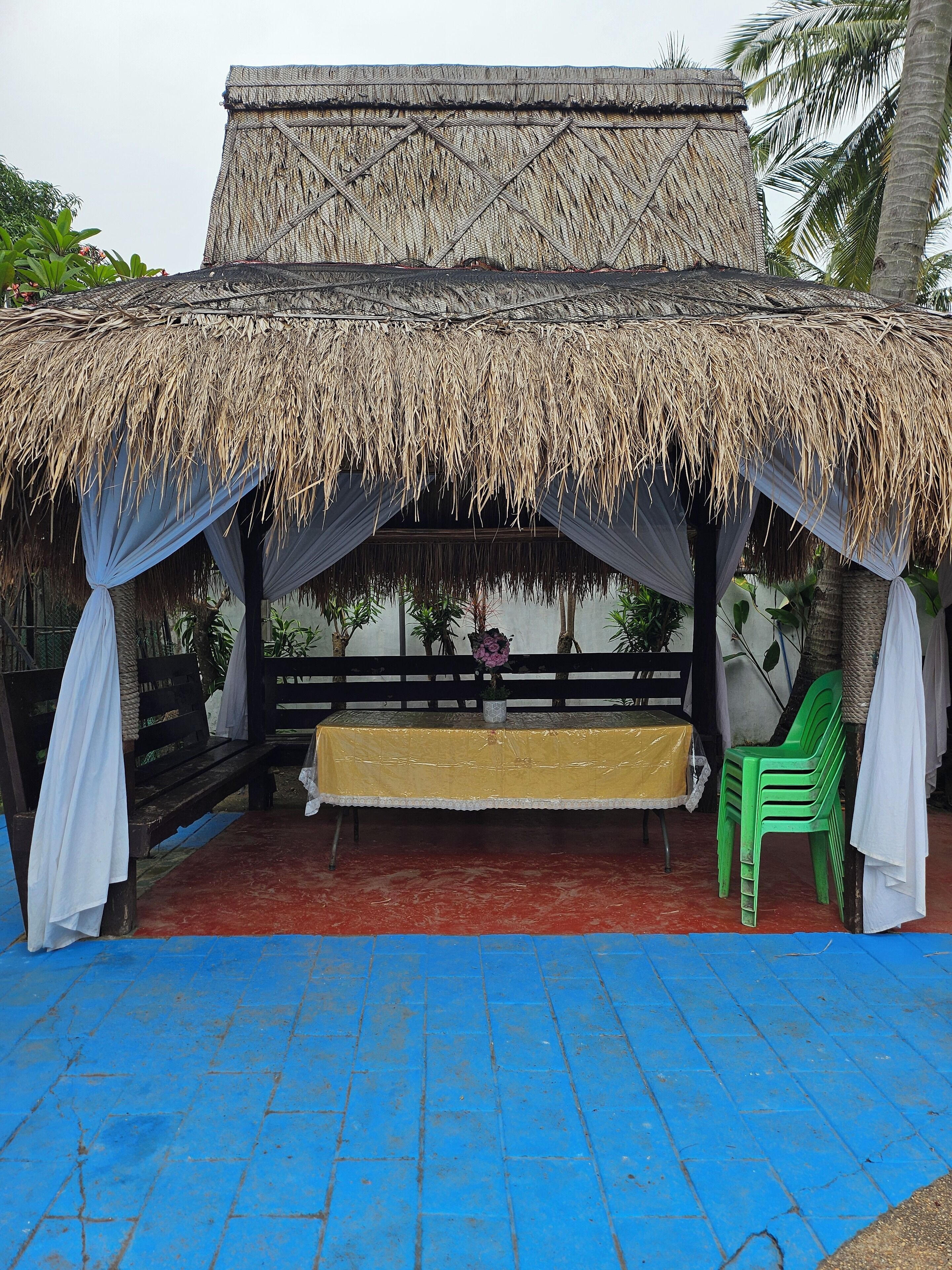 A thatched-roof structure with a bench and a table, surrounded by blue tiles.