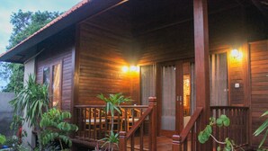 Una cabaña de madera con un porche, barandas de madera y una escalera que lleva a la entrada.