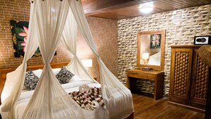 Un dormitorio con cama con dosel, una mesita de noche de madera, un espejo y un armario.