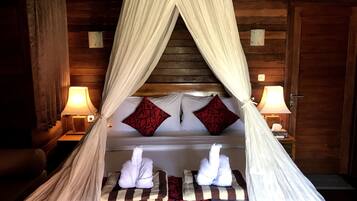 A bed with a canopy, two pillows, a bedside table with a lamp, and a wooden wall.