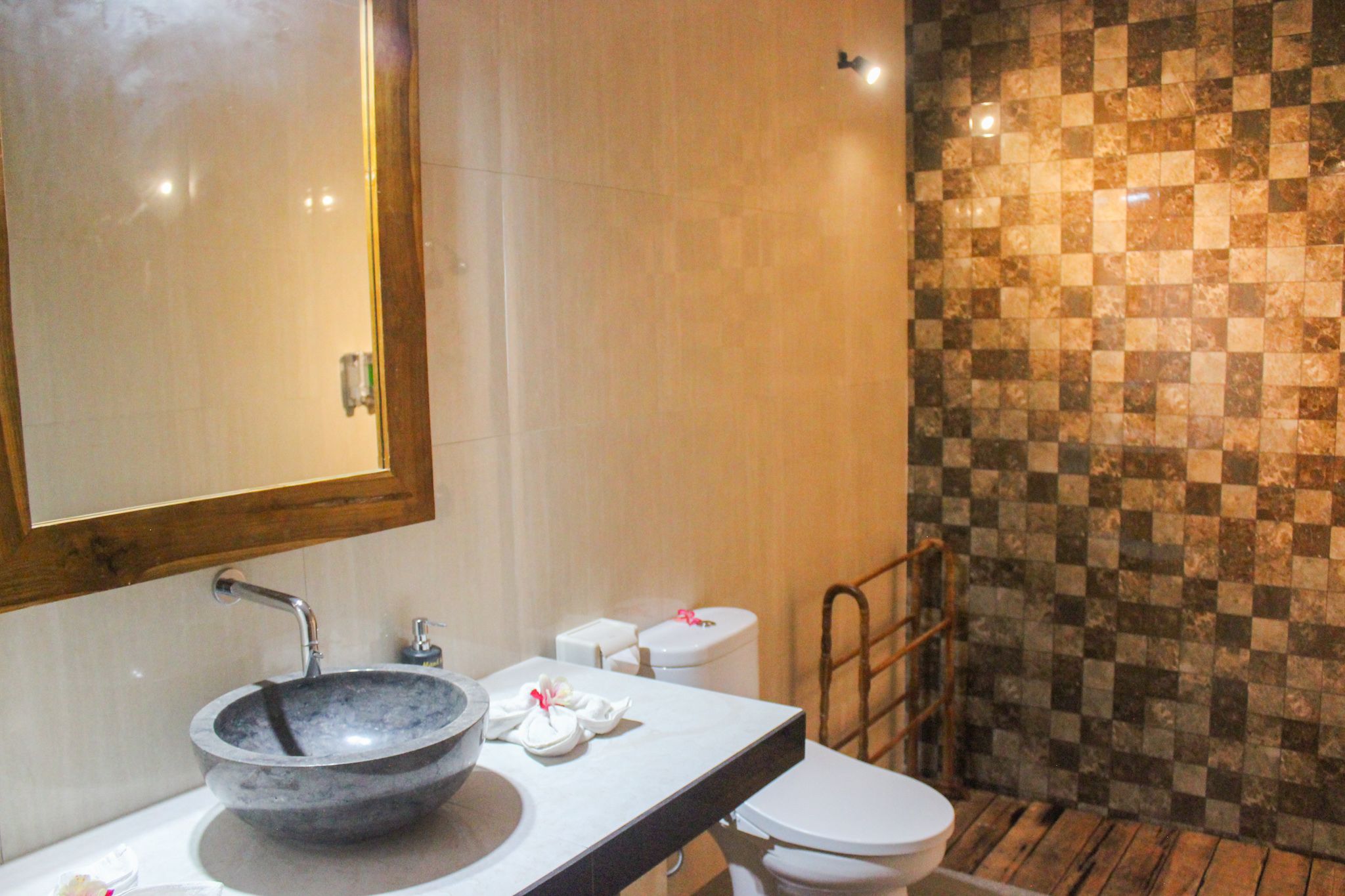 A bathroom with a marble sink, a mirror, a toilet, and a checkered wall.