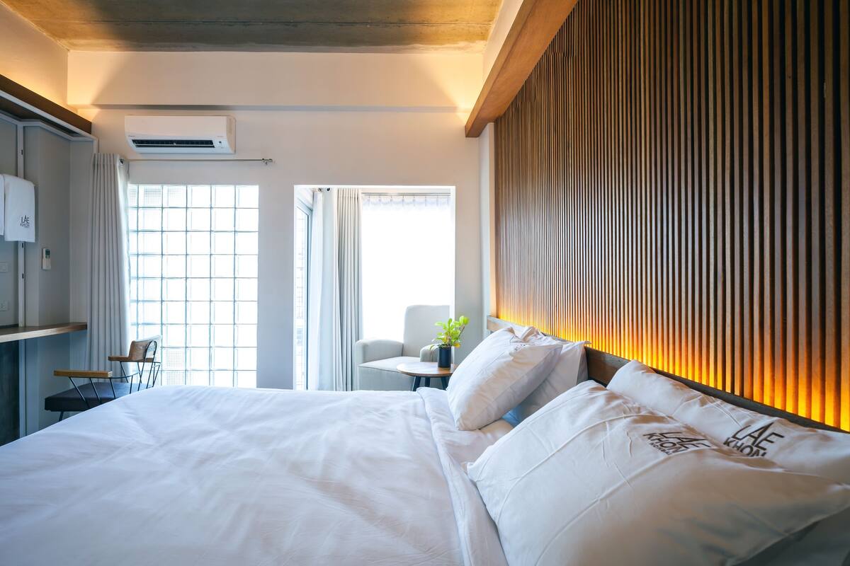 Habitación de hotel con una cama grande, un escritorio, una silla y una ventana con cortinas.