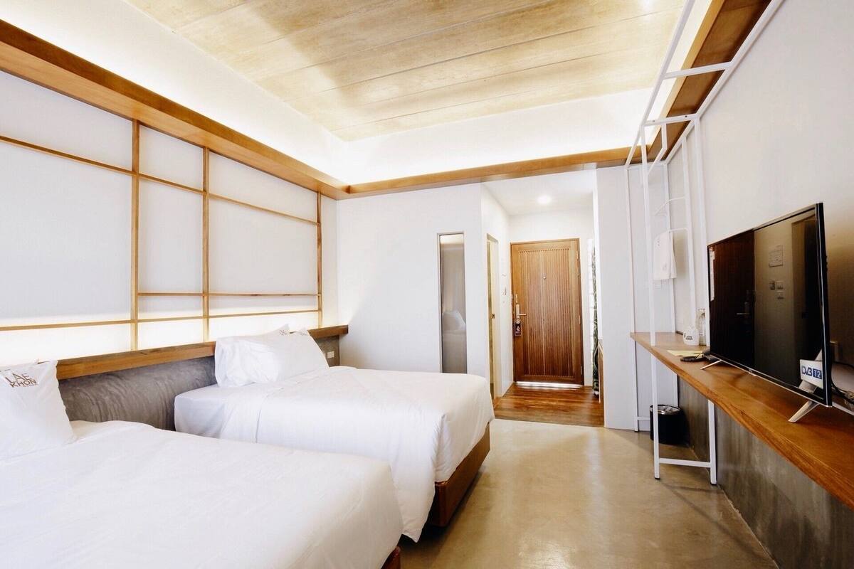 Habitación de hotel con dos camas, televisión y techo de madera.