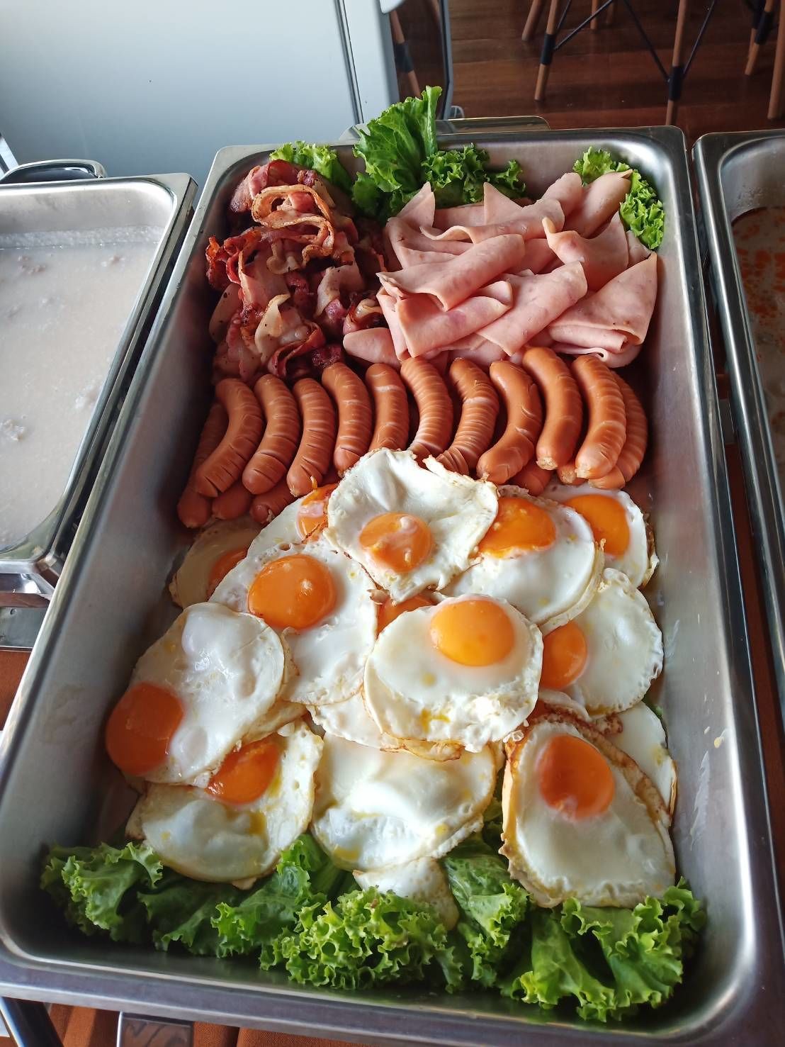 A buffet with various food items including sausages, ham, eggs, and lettuce.