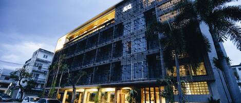 Un edificio moderno de varios pisos, con un balcón y una entrada bien iluminada.