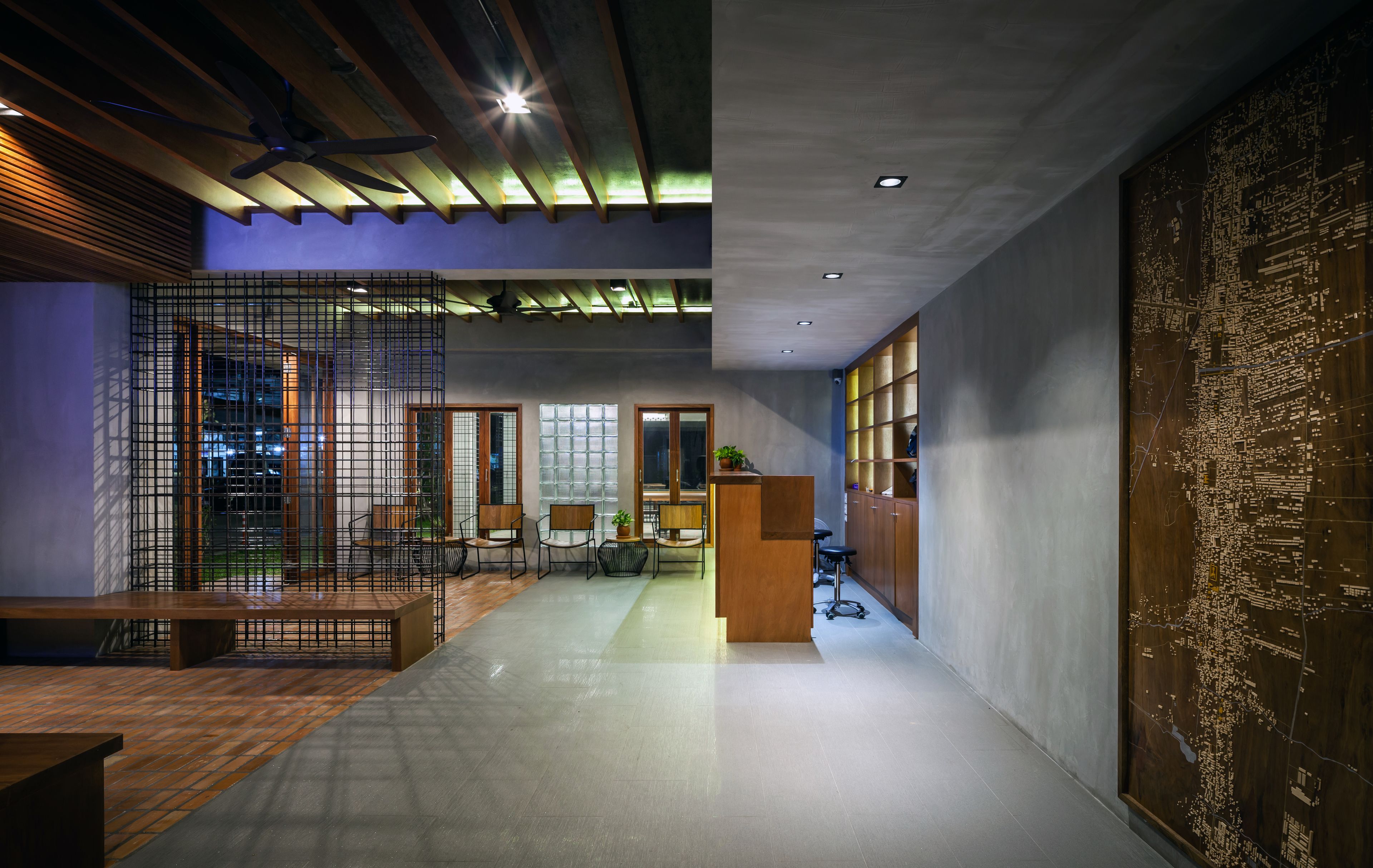 A modern interior with a wooden reception desk, seating area, and a large map on the wall.