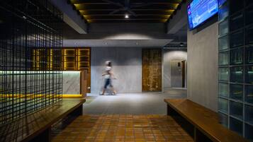 A modern interior with a tiled floor, wooden benches, a reception desk, and a digital display.