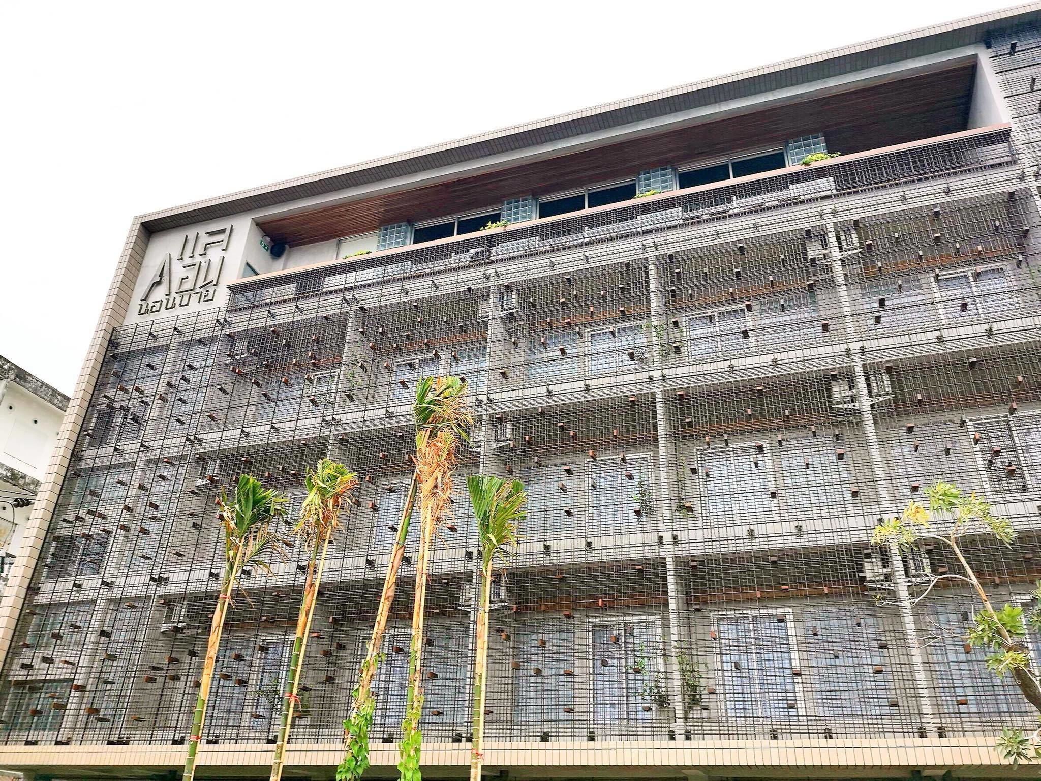 A multi-story building with a grid-like facade, featuring a series of vertical lines and small openings.
