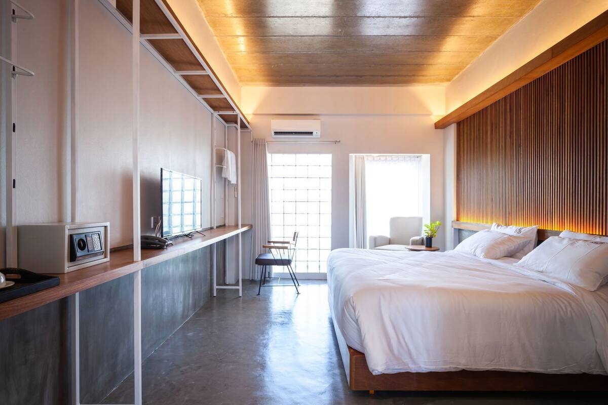 Habitación de hotel moderna con cama, escritorio, silla y ventana.
