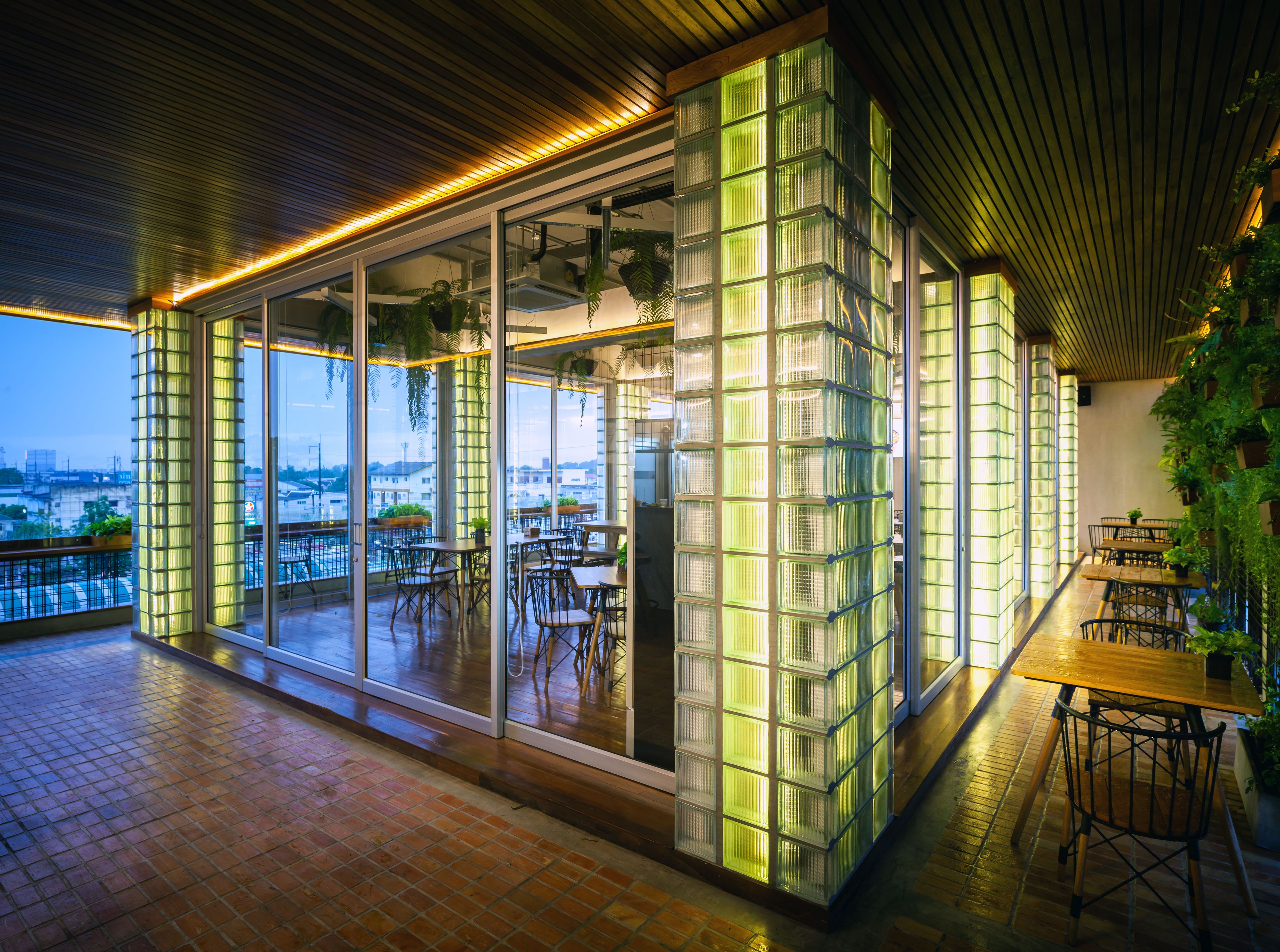 Un restaurante moderno con amplios ventanales de vidrio, piso de madera y vistas a la ciudad.