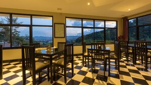 A dining area with a checkered floor, large windows with a view of the mountains, and a table set with chairs. - Pou Villa (Luang Namtha)