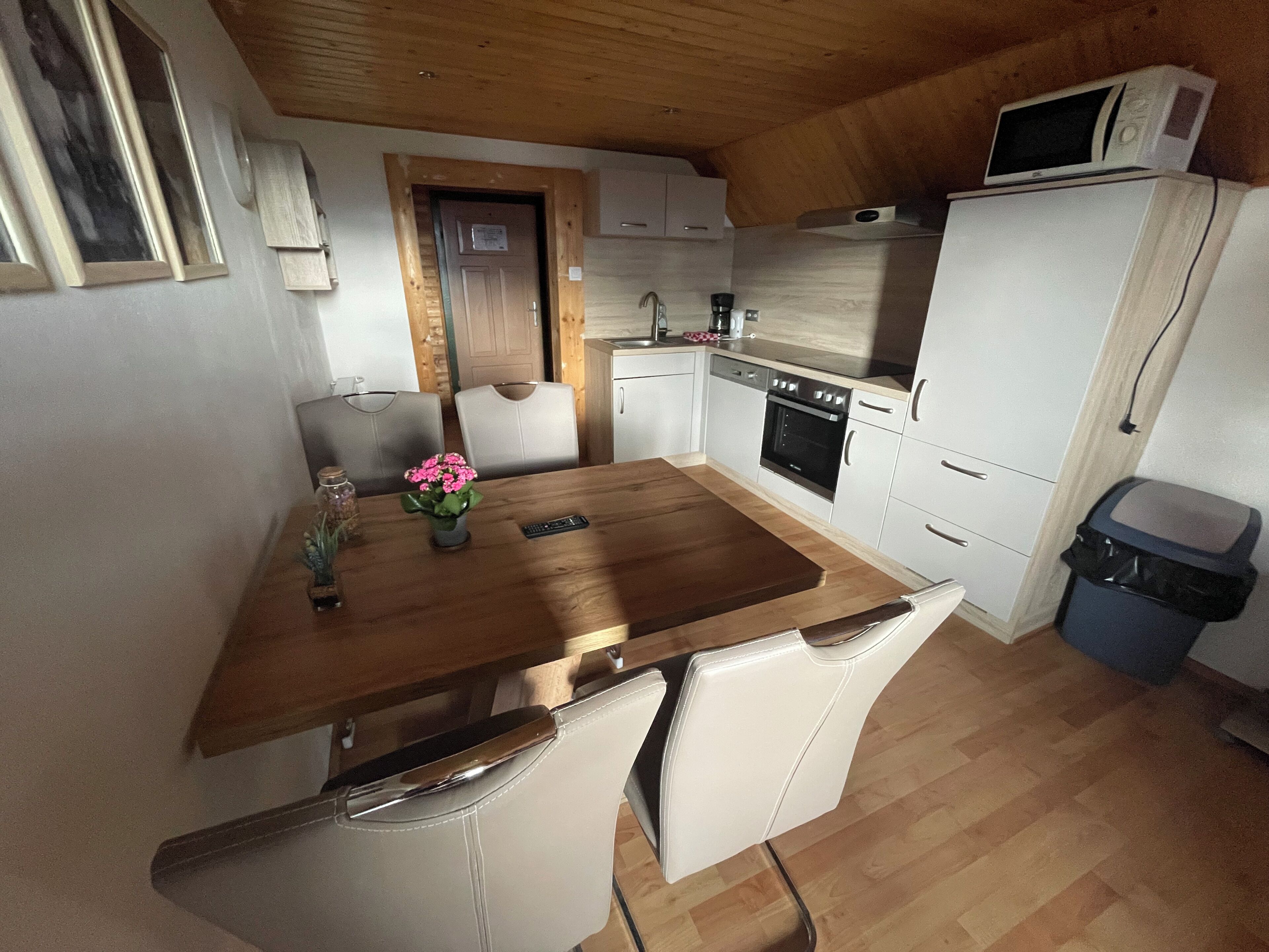 A compact kitchen with a wooden table, white cabinets, a built-in oven, and a microwave.