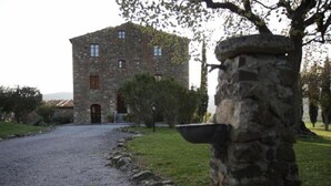 A stone building with a gravel driveway leading to a wooden door. - Agriturismo La Colombaia (Massa Marittima)