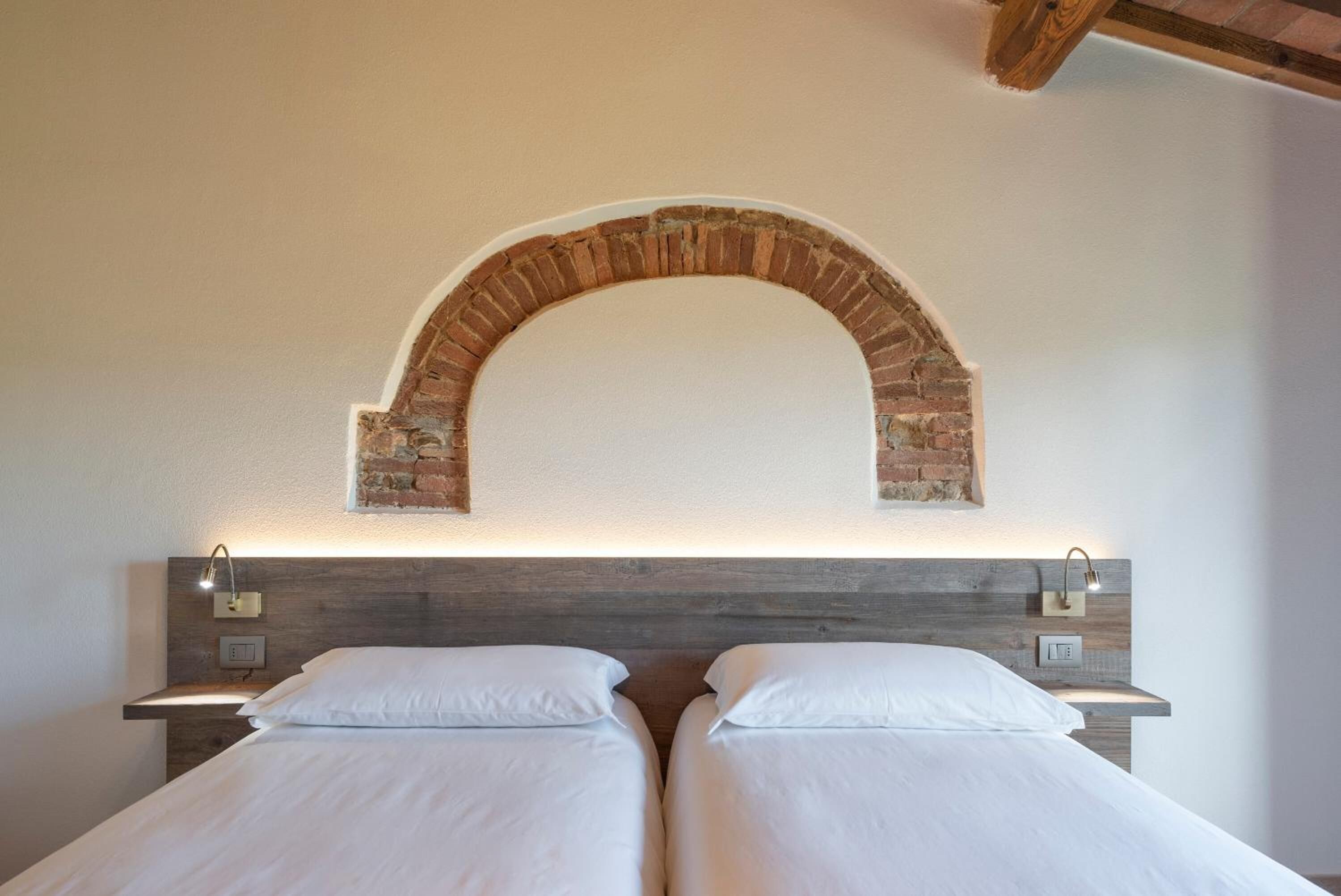 A double bed with a wooden headboard and a brick arch above it.