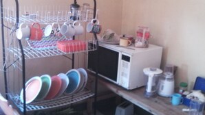 Une cuisine équipée d’un four à micro-ondes, d’une machine à café et d’une étagère contenant de la vaisselle et des ustensiles.