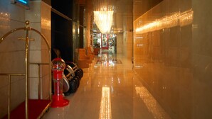 A hotel lobby with a red carpet, a red gumball machine, a chandelier, and a row of leather sofas. - Phoenicia Hotel (Dubai)