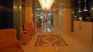 A hotel lobby with a reception desk, seating area, and a chandelier. - Phoenicia Hotel (Dubai)